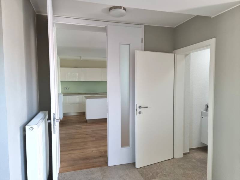 PREDAJ - 3 izbový dom v centre mesta, Nitra - Interiér rodinného domu s bielymi dverami a podlahou s dreveným dekorom.