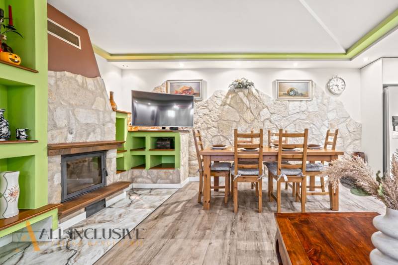 NA PREDAJ 5+2 IZBOVÝ RD PRI KÚPALISKU, DUNAJSKÁ STREDA - Interiér rodinného domu s krbom, kamennou stenou, jedálenským stolom a podlahou s dreveným dekorom.