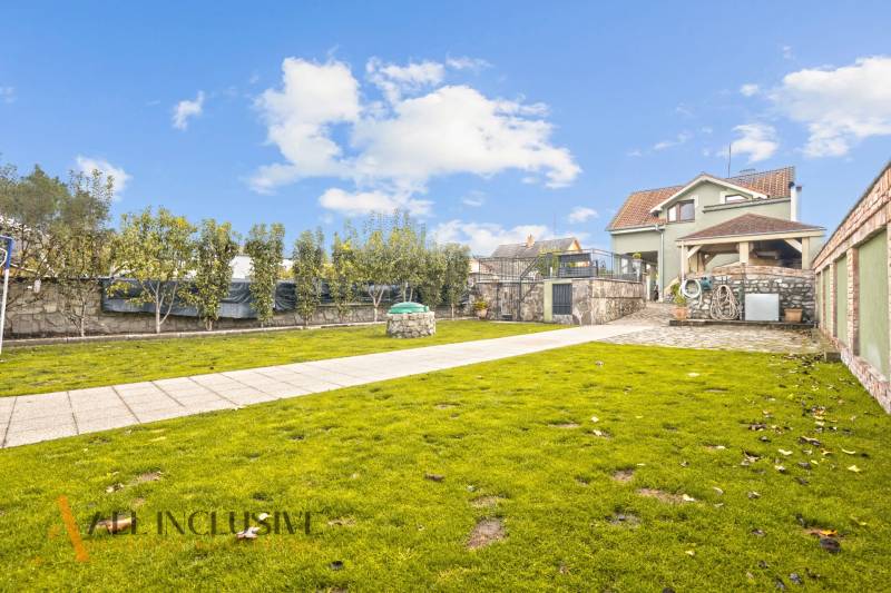 NA PREDAJ 5+2 IZBOVÝ RD PRI KÚPALISKU, DUNAJSKÁ STREDA - Záhrada rodinného domu na Kúpeľnej ulici v Dunajskej Strede s udržiavaným trávnikom a stromami.