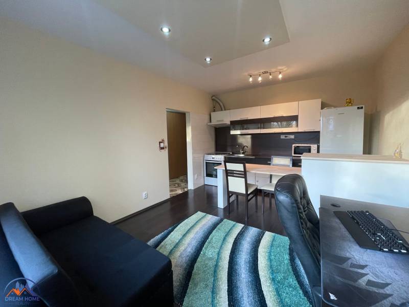 MH279-Na predaj 1 izbový byt v oblúbenej lokalite Komárna! - Interiér 1-izbového bytu s kuchynským kútom a podlahou s dreveným dekorom.