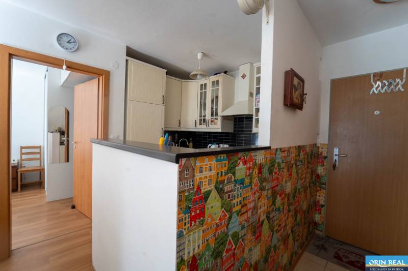 Na predaj útulný 2 izbový byt so zahradkou Svätý Jur 165.000,- Eur - Kuchyňa v 2-izbovom byte s farebnými mozaikami a podlahou s dreveným dekorom.