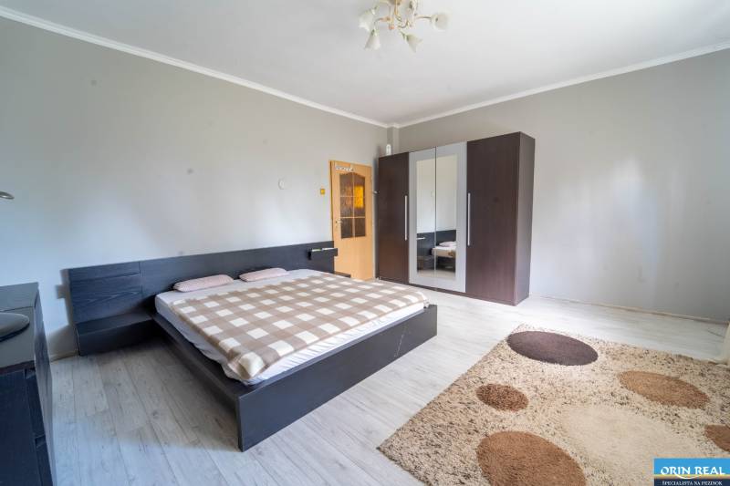 Na predaj rodinný dom s rozľahlým pozemkom 1788m2 MODRA - Spálňa v rodinnom dome s posteľou, šatníkom a podlahou s dreveným dekorom.