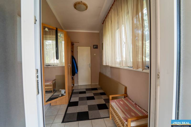 Na predaj rodinný dom s rozľahlým pozemkom 1788m2 MODRA - Vstupná hala rodinného domu s kobercami, závesmi a skrinkou s vešaním.