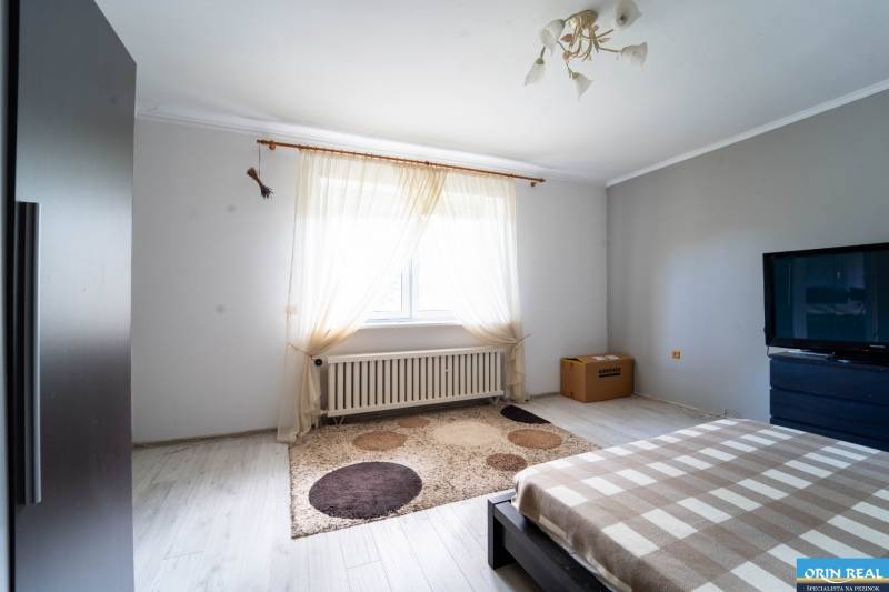 Na predaj rodinný dom s rozľahlým pozemkom 1788m2 MODRA - Svetlá spálňa s televízorom a koberec v rodinnom dome, podlaha s dreveným dekorom.