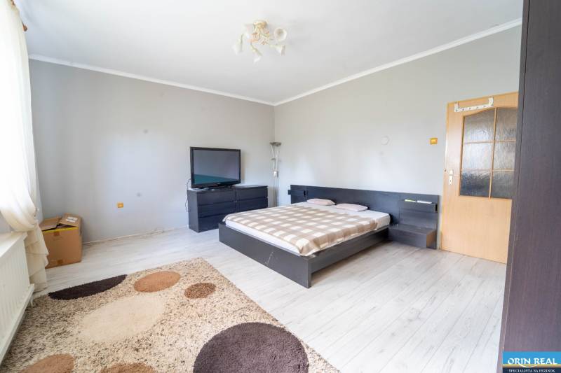 Na predaj rodinný dom s rozľahlým pozemkom 1788m2 MODRA - Spálňa v Rodinnom dome s posteľou, televízorom a podlahou s dreveným dekorom.