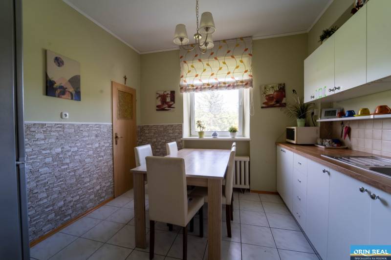 Na predaj rodinný dom s rozľahlým pozemkom 1788m2 MODRA - Kuchyňa v rodinnom dome s dreveným dekorom stola a bielymi skrinkami.