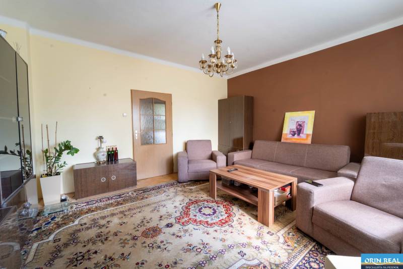 Na predaj rodinný dom s rozľahlým pozemkom 1788m2 MODRA - Obývačka v rodinnom dome s kobercovým vzorom, sedacou súpravou a svietidlom.