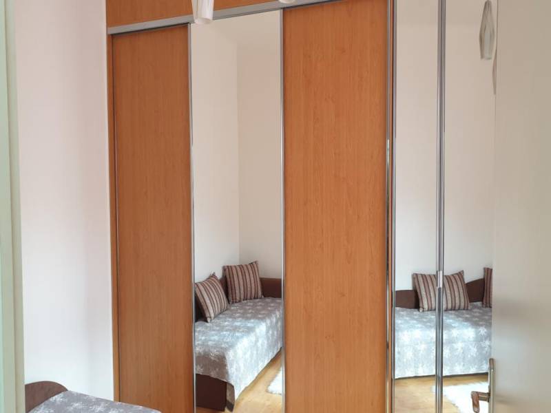 Novinka: Praktický byt v širšom centre. Mestská ul. Províziu neplatíte - Zrkadlová skriňa v 2-izbovom byte, odraz miestnosti so sedačkou a podlahou s dreveným dekorom.