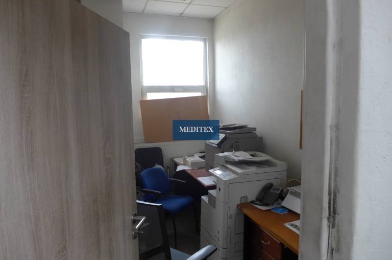 Sklad na prenájom o celkovej ploche 1015 m2 - Malá kancelária so stoličkami, tlačiarňou a oknom v skladoch a halách.