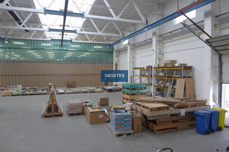 Sklad na prenájom o celkovej ploche 1015 m2 - V sklade sú palety so stavebným materiálom a regály s uloženými doskami.