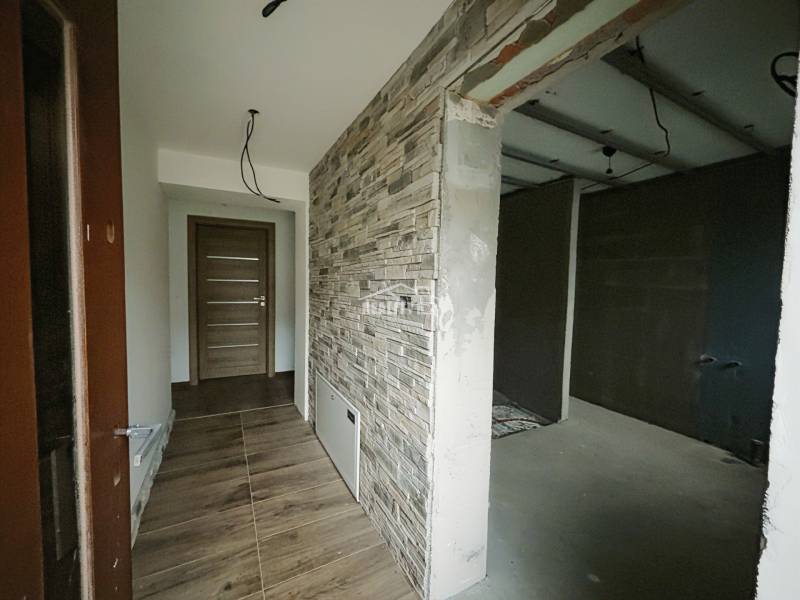 REZERVOVANÉ |Exkluzívne na predaj rodinný dom, Kolárovice (okres Bytča - Chodba so stenou s kameňovým dekorom a podlahou s dreveným dekorom v rodinnom dome.