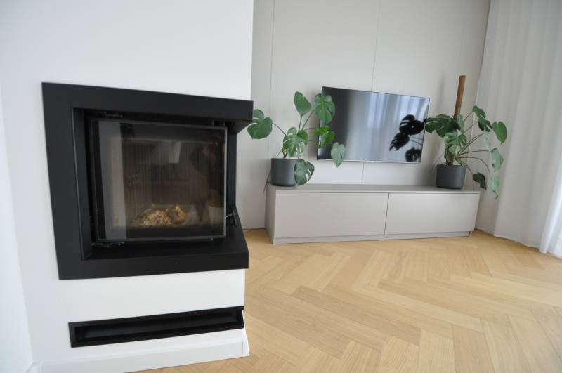 Perla v mori priemernosti - 4i prémiový RD Miloslavov - Obývačka v rodinnom dome s krbom, televízorom a podlahou s dreveným dekorom.