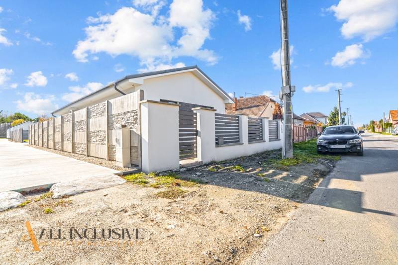 NA PREDAJ 4-IZB.BUNGALOV S DVOJGARÁŽOU,ORECHOVÁ POTôŇ - Rodinný dom v Orechovej Potôni s kamenným plotom a zaparkovaným autom na ulici.