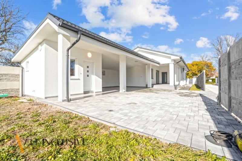 NA PREDAJ 4-IZB.BUNGALOV S DVOJGARÁŽOU,ORECHOVÁ POTôŇ - Rodinný dom v Orechovej Potôni s bielou fasádou a vydláždeným vstupom.