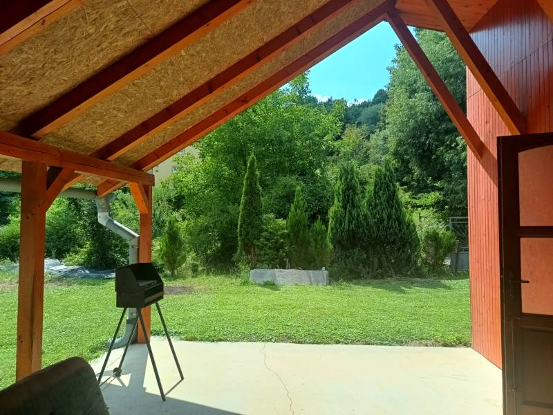 TUŽINA okres Prievidza - CHATA s terasou a garážou  - Krytá terasa pri chate v Tužine s výhľadom na zelený trávnik a stromčeky.