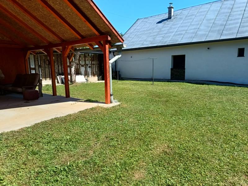 TUŽINA okres Prievidza - CHATA s terasou a garážou  - Záhrada pri chate v Tužine s prístreškom a trávnikom na slnečnom mieste.