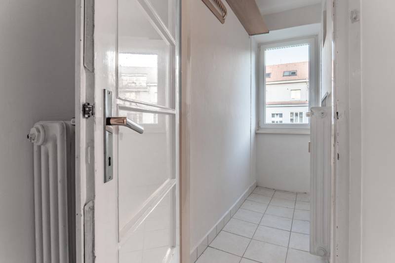 REZERVOVANÉ I Predaj charizmatického bytu Pavlovova ulica - Úzka miestnosť s oknom, dlaždicovou podlahou a bielym radiátorom v 3-izbovom byte.