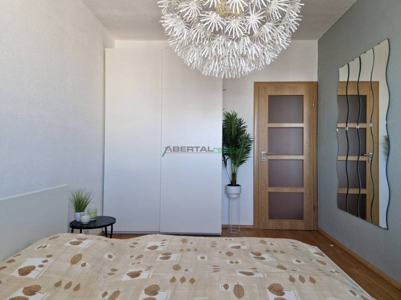 PRENÁJOM zariadený 3-izb byt, Pribišova, Bratislava - Spálňa s dekoratívnym svietidlom, šatníkovou skriňou a podlahou s dreveným dekorom v 3-izbovom byte.