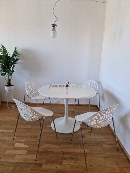 PRENÁJOM zariadený 3-izb byt, Pribišova, Bratislava - Jedálenský kút v 3-izbovom byte s podlahou s dreveným dekorom a ozdobnými stoličkami.