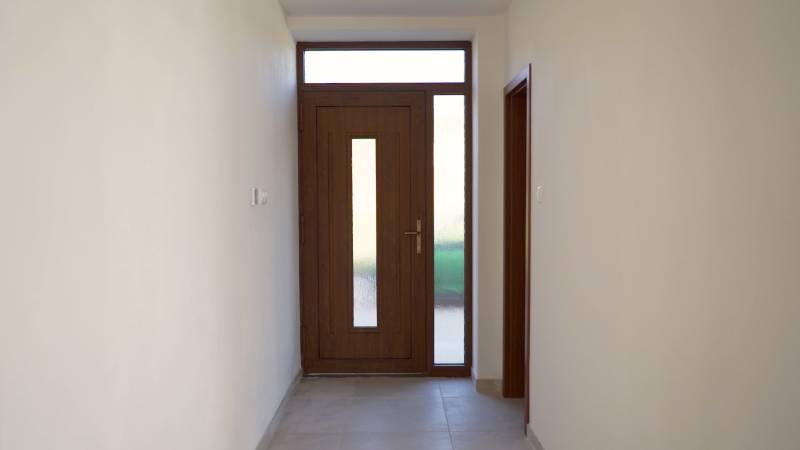 Predaj novostavba rodinného domu   Nová Baňa - Chodba v rodinnom dome s dverami z tmavého dreva a rovným stropom.