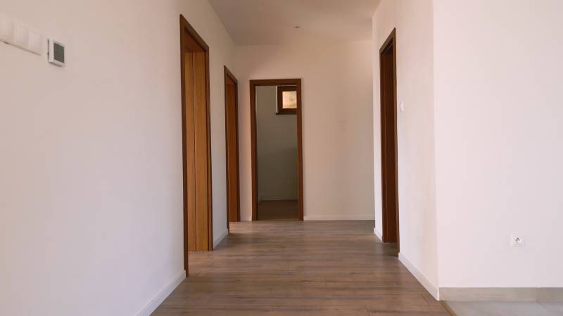 Predaj novostavba rodinného domu   Nová Baňa - Interiér rodinného domu s dreveným dekorom podlahy a bielymi stenami.