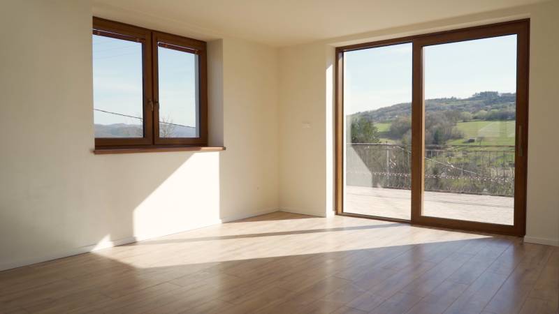 Predaj novostavba rodinného domu   Nová Baňa - Priestranné svetlé miestnosti v rodinnom dome s podlahou s dreveným dekorom a veľkými oknami.