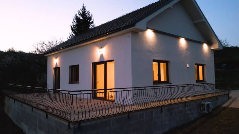Predaj novostavba rodinného domu   Nová Baňa - Rodinný dom v Novej Bani s terasou osvetlenou bodovými svetlami počas súmraku.