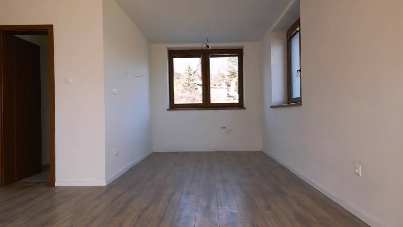 Predaj novostavba rodinného domu   Nová Baňa - Interiér rodinného domu s podlahou s dreveným dekorom, veľkým oknom a bielymi stenami.