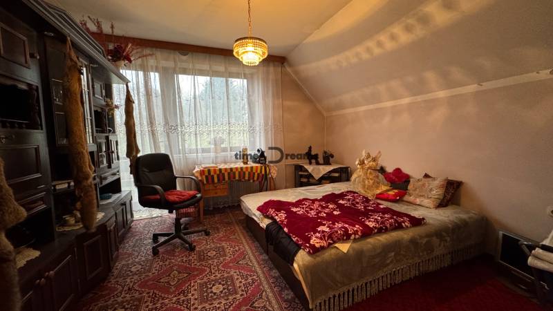 NA PREDAJ veľký rodinný dom v obci Pusté Úľany Sládkovičovo - Spálňa v rodinnom dome: koberec, posteľ, kreslo, vitrína, závesy, luster, dekorácie.