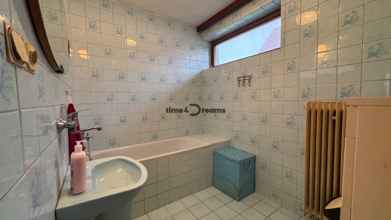 NA PREDAJ veľký rodinný dom v obci Pusté Úľany Sládkovičovo - Kúpeľňa s vaňou v rodinnom dome, bledomodré obklady, okno, umývadlo, radiátor.