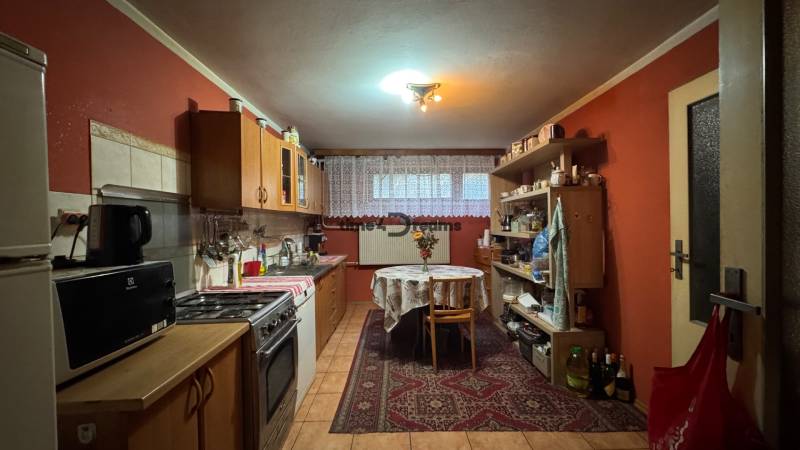 NA PREDAJ veľký rodinný dom v obci Pusté Úľany Sládkovičovo - Tradičná kuchyňa v rodinnom dome s dreveným nábytkom a červenými stenami, vybavená spotrebičmi.