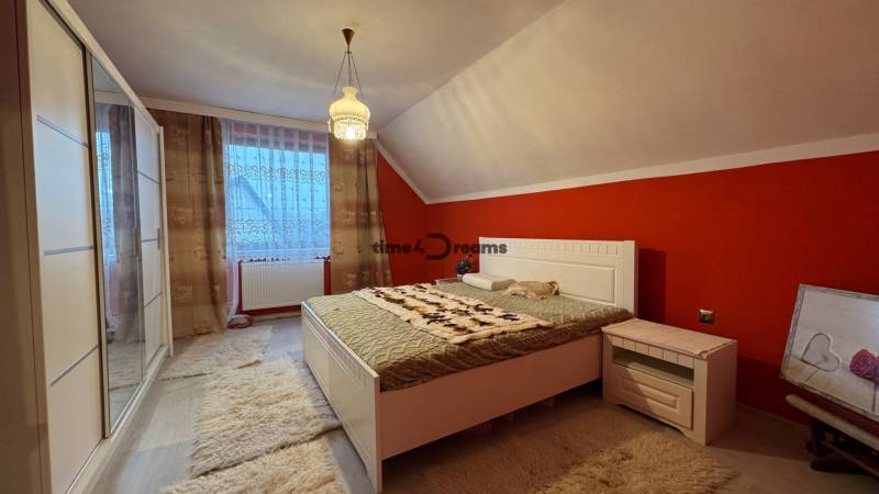 NA PREDAJ veľký rodinný dom v obci Pusté Úľany Sládkovičovo - Spálňa v rodinnom dome so šikmým stropom, červenou stenou a bielym nábytkom.