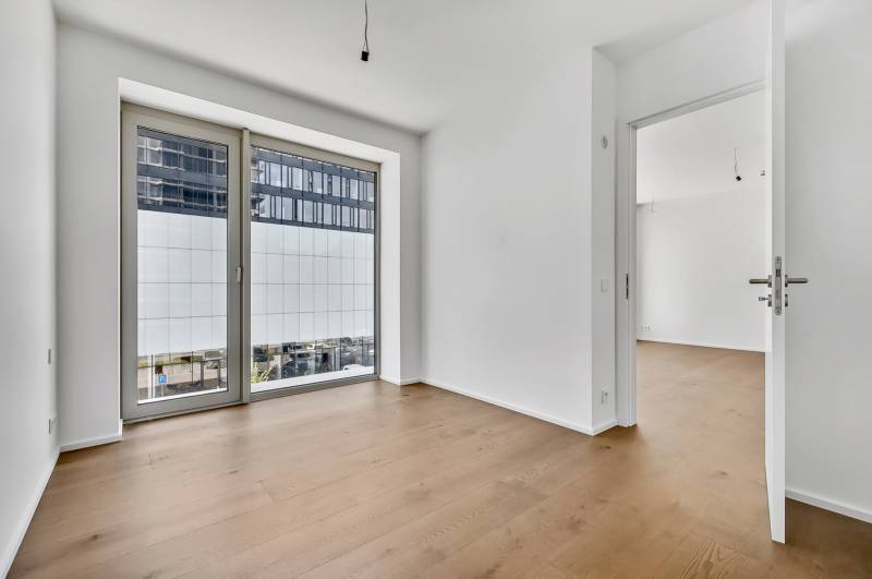 PREDAJ - LIGET Nový 2 izbový apartmán pri Sade Janka Kráľa, Petržalka - Izba s drevenou podlahou a veľkým oknom v 2-izbovom byte.