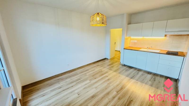 Na prenájom 1 i byt 47 m2 v Partizánskom na sídlisku Luhy 2 x balkón - Kuchyňa v 1-izbovom byte s bielymi skrinkami a podlahou s dreveným dekorom.