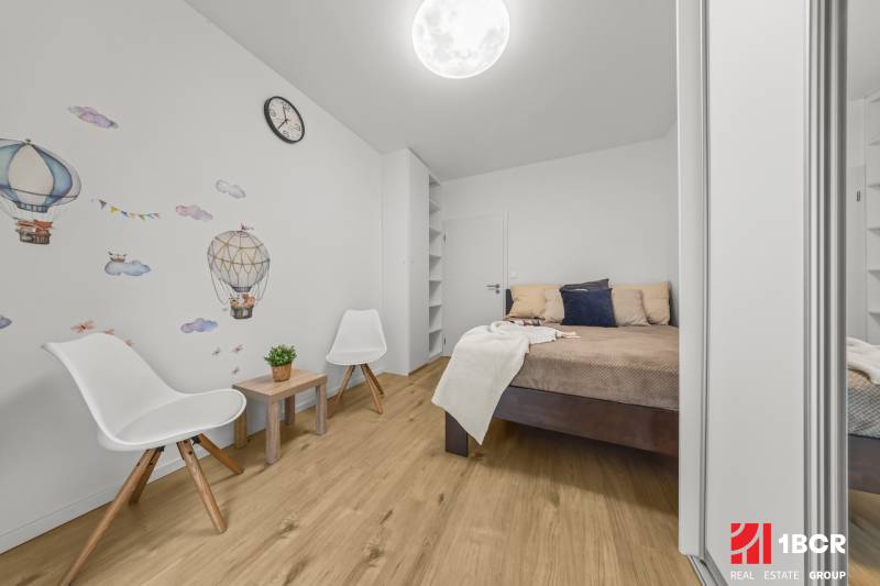 NOVOSTAVBA 2-IZB.BYT,ZÁHRADKA 26 m²,PARK.STÁTIE, MAHULANKA,PEZINOK - Spálňa v 2-izbovom byte s dekorom na stene a podlahou s dreveným dekorom.