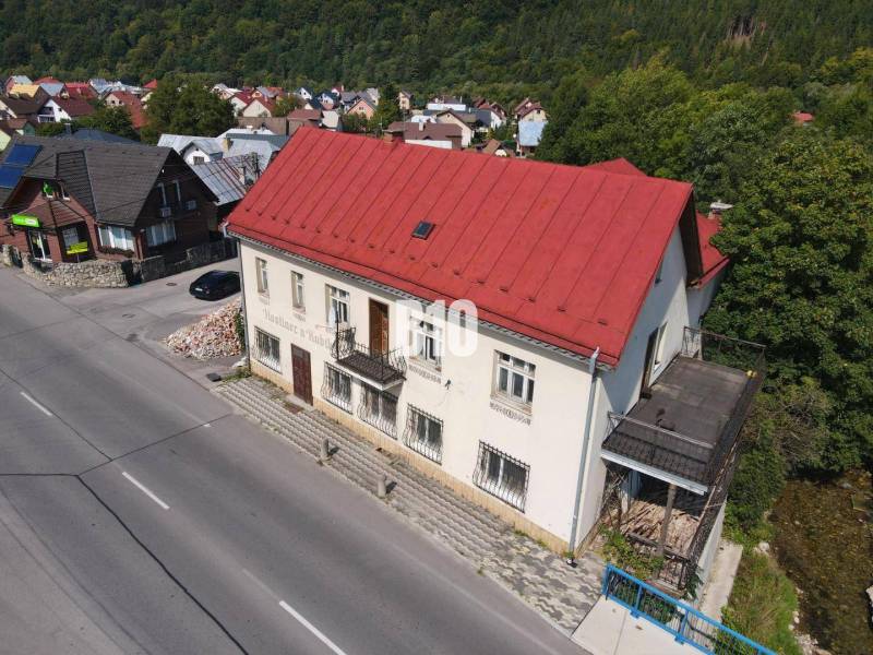 Teraz zľava 30.000 TOP INVESTIČNÁ PRÍLEŽITOSŤ Polyfunkčný objekt na pr - Budova v Belej s červenou strechou, okolité domy a príroda.