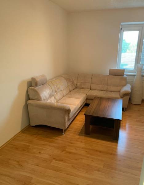 2-izb. byt, Tylova ul., Nové Mesto, tehlový dom - Obývacia izba s pohodlnou sedačkou a stolíkom na podlahe s dreveným dekorom.