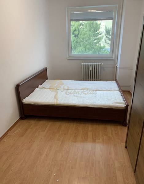 2-izb. byt, Nobelova ul., Nové Mesto, 2.p./7, balkón - Spálňa s posteľou, radiátorom a podlahou s dreveným dekorom v 2-izbovom byte.