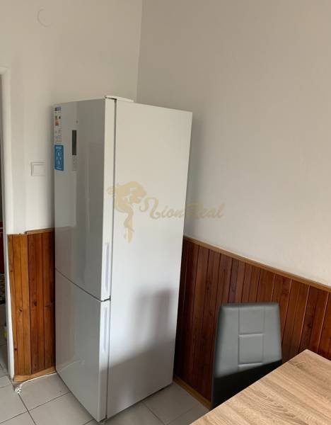 2-izb. byt, Nobelova ul., Nové Mesto, 2.p./7, balkón - Kuchyňa v 2-izbovom byte s chladničkou, tmavým obkladom a jedálenským kútom.