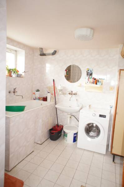 Rodinný dom v obci Čilížska Radváň s veľkým pozemkom - Kúpeľňa v rodinnom dome s práčkou a umývadlom, jednoduchý štýl, svetlé obklady.