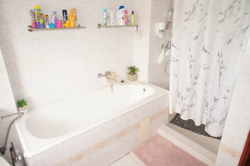 Rodinný dom v obci Čilížska Radváň s veľkým pozemkom - Kúpeľňa s vaňou, pestrofarebné doplnky, záves a rastliny v horskom rodinnom dome.