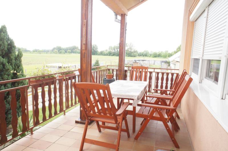 Rodinný dom v obci Čilížska Radváň s veľkým pozemkom - Rodinný dom má terasu s drevenými stoličkami a stolíkom, výhľad na záhradu.