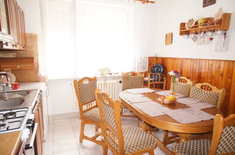 Rodinný dom v obci Čilížska Radváň s veľkým pozemkom - Kuchyňa rodinného domu s dreveným obložením, jedálenským stolom a nástennými dekoráciami.