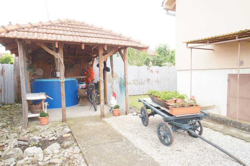 Rodinný dom v obci Čilížska Radváň s veľkým pozemkom - Altánok s modrou nádobou, bicyklom a vozom s kvetináčmi pri rodinnom dome.