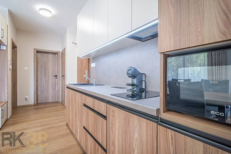 Lukratívne dvoj a štvorizbové byty v Tatranskej Lomnici na prenájom - Kuchyňa v 2-izbovom byte s podlahou s dreveným dekorom a moderným vybavením.
