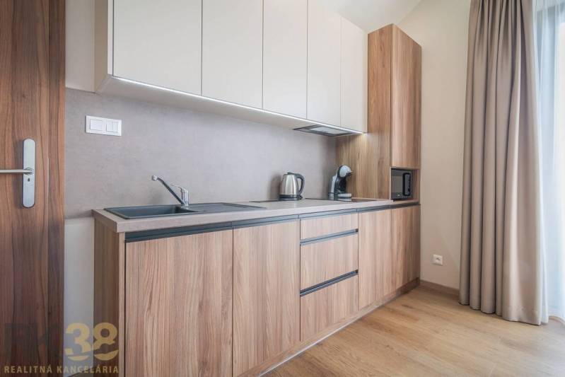 Lukratívne dvoj a štvorizbové byty v Tatranskej Lomnici na prenájom - Kuchyňa v 2-izbovom byte s podlahou s dreveným dekorom a svetlou linkou.