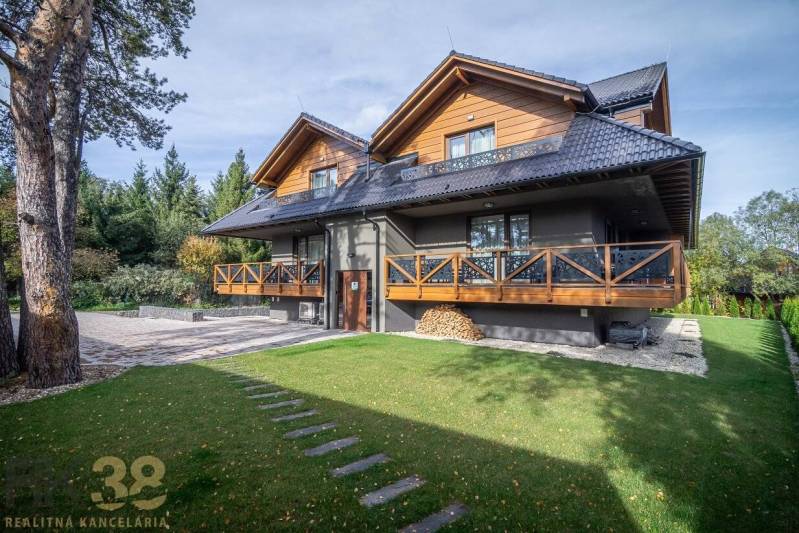 Lukratívne dvoj a štvorizbové byty v Tatranskej Lomnici na prenájom - Dvojposchodový dom s drevenými prvkami a zeleným trávnikom v Tatranskej Lomnici.