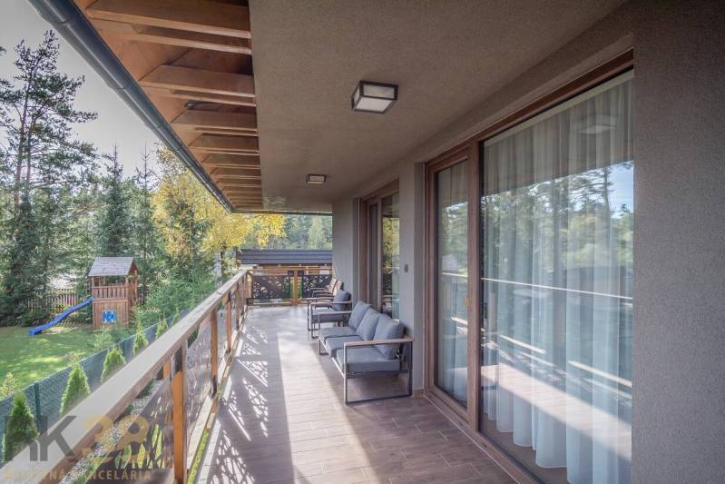 Lukratívne dvoj a štvorizbové byty v Tatranskej Lomnici na prenájom - Balkón 2-izbového bytu v Tatranskej Lomnici s podlahou s dreveným dekorom a výhľadom na zeleň.