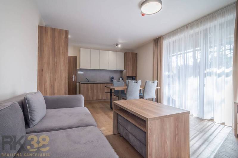 Lukratívne dvoj a štvorizbové byty v Tatranskej Lomnici na prenájom - Obývacia izba v 2-izbovom byte s nábytkom a podlahou s dreveným dekorom.