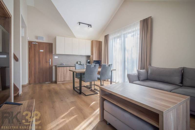 Lukratívne dvoj a štvorizbové byty v Tatranskej Lomnici na prenájom - Svetlý 2-izbový byt s podlahou s dreveným dekorom, pohodlným sedením a kuchyňou.